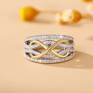 Macro view of wide silver ring with layered pavé zircons and golden infinity symbol