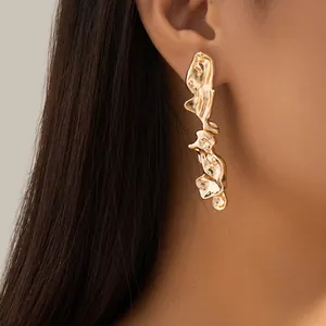 Golden irregular liquid metal earrings with molten texture on female model