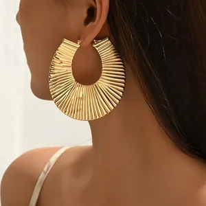 Golden retro U-shaped hoop earrings with pleated texture worn by a model