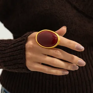 Close-up of a large oval red gemstone ring on a hand with gold polished finish metal