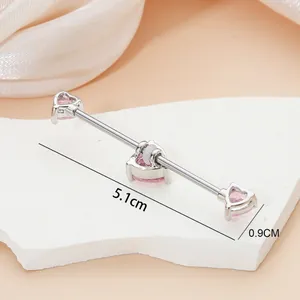5.1cm industrial barbell piercing with pink heart zircons on white stone stand