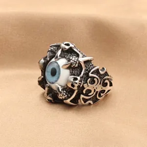 Detail of vintage punk dragon claw ring with realistic blue eye in silver stainless steel