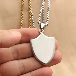 Detail of shield pendant with brushed steel texture on silver and gold box chains