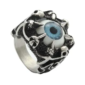 Gothic punk titanium steel ring with blue eyeball and sculpted skulls on white background