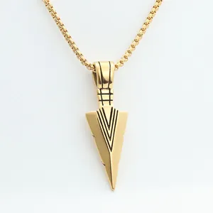 Detail of a golden spearhead pendant featuring black geometric engraved patterns on a box chain