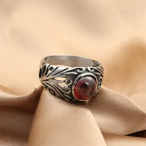 Anello vintage in acciaio inossidabile con gemma rossa ovale su sfondo di seta champagne