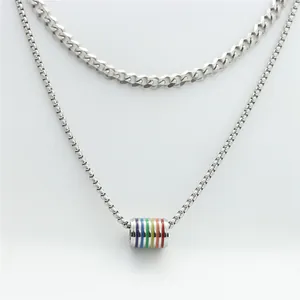Macro detail of silver double layer chain necklace featuring a rainbow stripe tube pendant