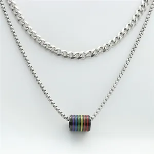 Detail of silver stainless steel double chain featuring a cylindrical rainbow pride pendant