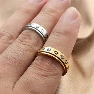 Detail of spinning stainless steel rings with black daisy patterns in gold and silver finish