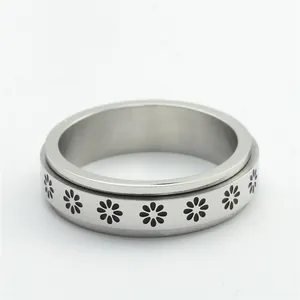 Detailed macro view of a stainless steel spinner ring featuring engraved daisy patterns
