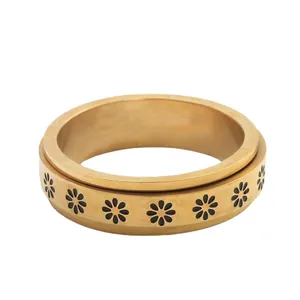 Rotating stainless steel spinner ring with golden daisy flower pattern on a white background