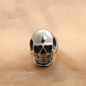 Detailed view of punk style silver polished stainless steel skull ring on satin fabric