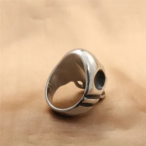 Polished stainless steel skull ring in punk style, displayed on gold satin background