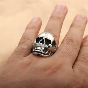 Macro detail of men's punk skull ring in retro silver finish on a textured background