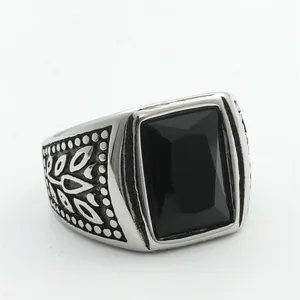 Macro shot of retro men's steel ring with square black stone and leaf carvings