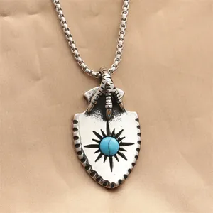 Macro shot of punk eagle claw shield pendant with turquoise stone on silk fabric