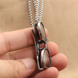 Macro detail of hand holding a creative punk style mini sunglasses pendant on box chain