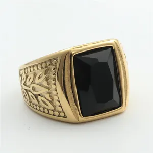 Macro detail of men's vintage gold ring with rectangle black stone and embossed patterns