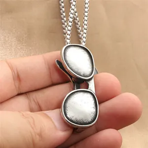 Punk style stainless steel sunglasses pendant necklace with vintage finish held in hand