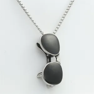 Macro detail of aviator sunglasses pendant in silver stainless steel with black enamel lenses