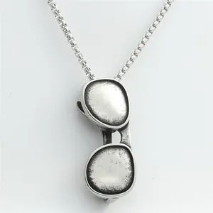 Macro detail of vintage punk style folding sunglasses pendant with a matte box chain finish