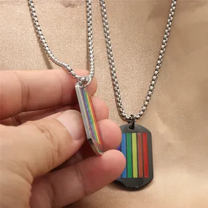 Dettaglio dei ciondoli dog-tag a strisce arcobaleno in argento e nero su seta dorata