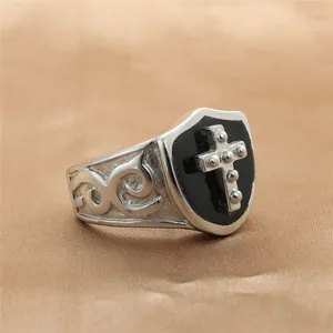 Detail of vintage punk steel ring featuring a black shield and silver cross emblem