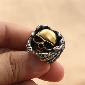 Macro-opname van een gothic schedelring met gouden hoofd en zilveren veren in vintage staal