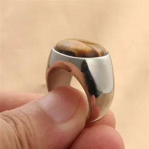 Detalle de una piedra ojo de tigre ovalada engastada en un anillo de acero inoxidable pulido