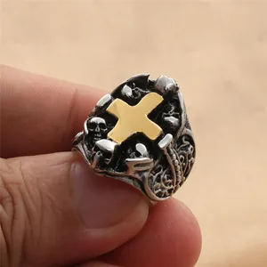 Detalle de un anillo gótico vintage con cruz dorada y motivos de calaveras en relieve