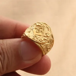 Détail macro bague franc-maçon dorée avec emblème compas G et relief floral