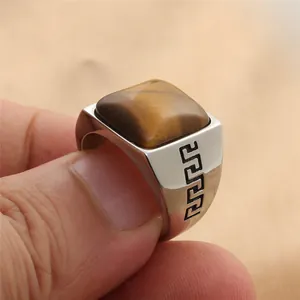 Primer plano de piedra ojo de tigre cuadrada y grabado de greca en anillo de acero