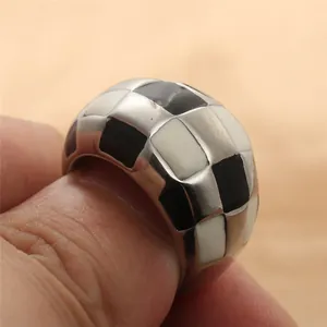 Macro detail of silver stainless steel ring with black and white checkerboard enamel pattern