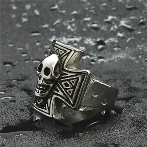 Punk style stainless steel skull ring with iron cross relief on black textured background