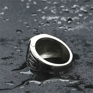 Retro punk titanium steel ring with gothic cross relief on a dark stone surface