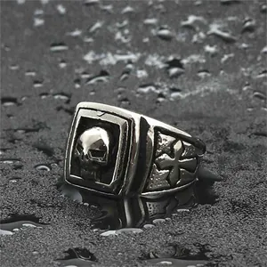 Vintage punk men's titanium steel skull ring with cross engraving on a dark wet background