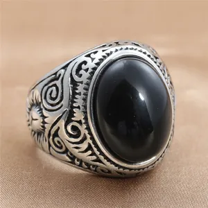Detalle de anillo vintage plateado con piedra negra y grabados florales sobre seda fina