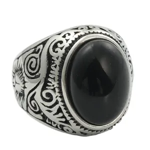 Primer plano de un anillo vintage de acero titanio con piedra negra ovalada y grabado
