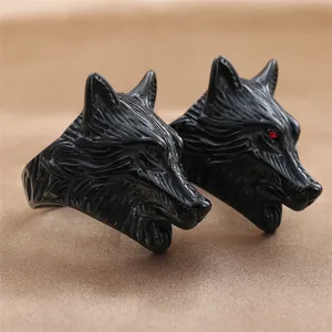 Detailed close-up of a black wolf head punk ring with red gemstone eyes on silk fabric
