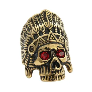 Detailed view of vintage gold punk skull ring with red eyes and feather headdress