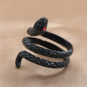 Macro view of black stainless steel snake ring featuring red gemstone eyes and scale texture