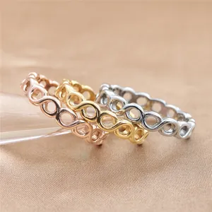 Dettaglio di tre anelli a catena con nodo infinito in acciaio oro rosa, oro e argento lucido