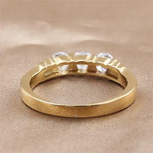 Anillo de acero inoxidable dorado con tres circonitas redondas en banda texturizada