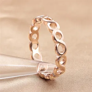 Dettaglio dell'anello a infinito oro rosa su supporto di cristallo e sfondo di seta
