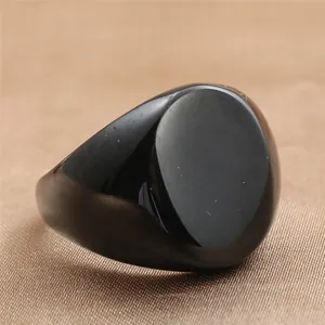 Primer plano de un anillo de sello negro pulido para hombre en fondo de seda marrón