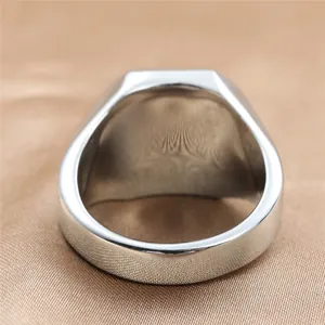 Polished silver stainless steel signet ring for men on a champagne satin background