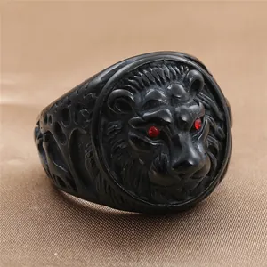 Detailed view of matte black lion head ring with red rhinestone eyes and side carvings