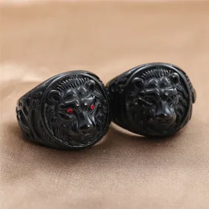 Macro shot of two black stainless steel lion rings with red stone eyes and ornate carvings