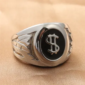 Macro detail of silver steel ring with black dollar sign inlay and leaf engravings