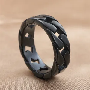 Detail of a matte black stainless steel curb chain ring on a silk fabric background